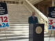 Photo shows Secretary of State Raffensperger at a podium with two posters on either side announcing the Presidential Primary 2024 date in Georgia as March 12, 2024 (Rahul Bali / WABE News photo).