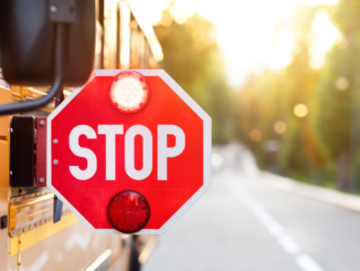 Photo shows a stop sign displayed on the side of a school bus (stock photo).