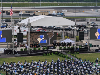 Photo of the graduation stage and graduates seated on the AMS infield grass at the Luella High School graduation in 2022 (Kimberly Sheppard photo).