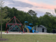Photo shows a playground with a restroom building in the background at East Hampton Community Park (Clayton Carte photo).